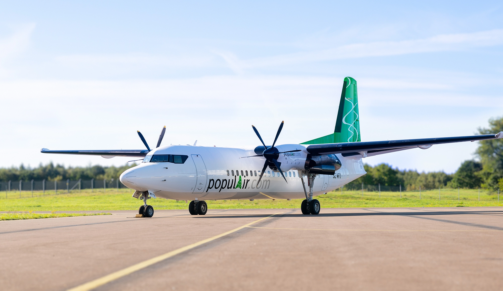 Fokker 50 - a white airplane with a green fin under sunny skies